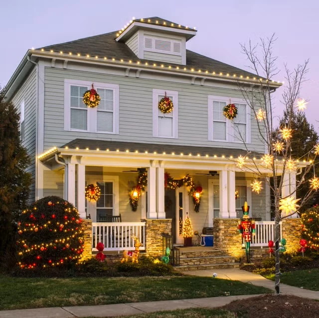 Two-story home with warm-white Christmas roofline lights, wreaths and seasonal decorations
